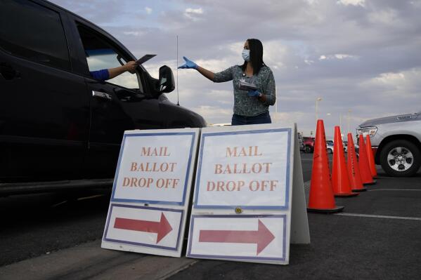 FILE - A county worker collects mail-in ballots in a drive-thru mail-in ballot drop off area at the Clark County Election Department, Nov. 2, 2020, in Las Vegas. Voting could feel different in this year's midterms, as the election falsehoods told by former President Donald Trump and many of his supporters have created a ripple effect across the country. (AP Photo/John Locher, File)