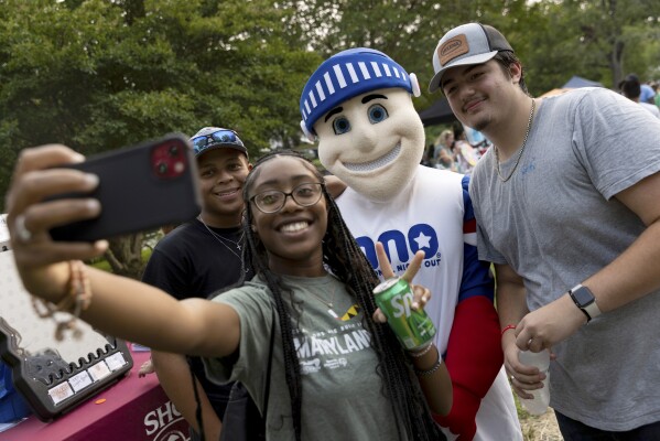 People take a selfie with the National Night Out mascot, Tuesday, August 1, 2023, in Salisbury, Md. The event, hosted by the Salisbury Police Department, aims to promote stronger community relationships and includes a number of organizations that provide support services to families.(APPhoto/Julia Nikhinson)