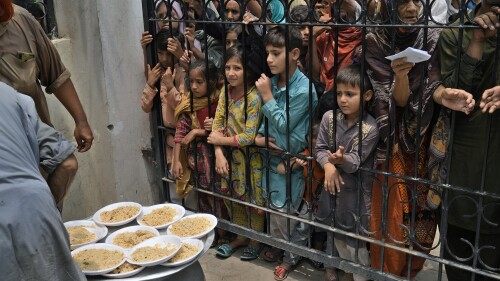 Women and children wait for free food at a distribution point in Lahore, Pakistan, on Tuesday, June. 27, 2023. (AP Photo/K.M. Chaudary)