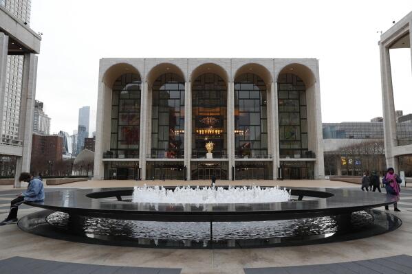 FILE - People appear in  Josie Robertson Plaza in front of The Metropolitan Opera house at Lincoln Center in New York on March 12, 2020. The Metropolitan Opera sold 56% of the dollar capacity of its tickets this season, managing to get through 196 staged performances without a cancellation but down from 69% during the last pre-pandemic season of 2018-19. (AP Photo/Kathy Willens, File)
