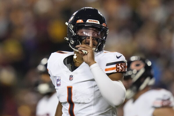 Chicago Bears quarterback Justin Fields (1) gestures after throwing a touchdown pass to wide receiver DJ Moore during the first half of an NFL football game against the Washington Commanders, Thursday, Oct. 5, 2023, in Landover, Md. (AP Photo/Alex Brandon)