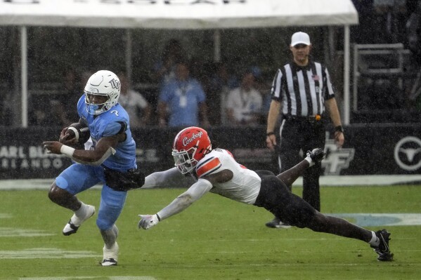 Central Florida running back RJ Harvey (7) dodges a tackle by Oklahoma State safety Trey Rucker, right, during the first half of an NCAA college football game, Saturday, Nov. 11, 2023, in Orlando, Fla. (AP Photo/John Raoux)