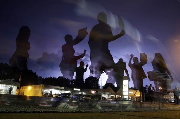 FILE - Protesters march in the street as lightning flashes in the distance in Ferguson, Mo., Aug. 20, 2014, following the shooting of Michael Brown, an unarmed Black teen, in the St. Louis suburb on Aug. 9. A legal nonprofit announced Tuesday, Feb. 27, 2024 that Ferguson has agreed to pay $4.5 million to settle a so-called debtors' prison lawsuit that accused the city of making money for its coffers over fines and court costs. (AP Photo/Jeff Roberson, File)