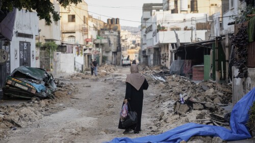 امرأة فلسطينية تسير على طريق مدمر بعد أن سحب الجيش الإسرائيلي قواته من معقل للمسلحين في مخيم جنين للاجئين في الضفة الغربية ، الأربعاء ، 5 يوليو ، 2023.  أنهى انسحاب القوات من المخيم حملة قمع استمرت يومين أسفرت عن مقتل ما لا يقل عن 13 فلسطينيًا ، وأجبرت الآلاف على النزوح من منازلهم وألحقت أضرارًا جسيمة في أعقابها.  كما قتل جندي إسرائيلي.  (AP Photo / مجدي محمد)