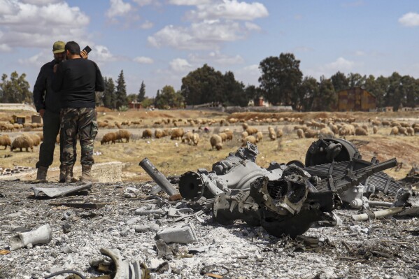 Two Syrian army officers inspect the site of an Israeli strike at a military airbase near Hama, Syria, Thursday April 3 2025.(AP Photo)