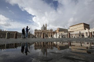 FILE - In this Sunday, Jan. 31, 2021 file photo, people are reflected on a puddle as they walk in St. Peter's Square, at the Vatican. The Vatican is taking Pope Francis’ pro-vaccine stance very seriously: Any Vatican employee who refuses to get a coronavirus shot without valid medical reason risks being fired.
A Feb. 8 decree signed by the governor of the Vatican City State sparked heated debate Thursday, Feb. 18, 2021 since its provisions go well beyond the generally voluntary nature of COVID-19 vaccinations in Italy and much of the rest of the world. (AP Photo/Alessandra Tarantino, File)