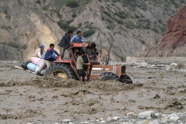 A tractor transporting farmers' produce to sell at the markets, crosses the La Paz river inundated by a mudslide due to persistent rains, in El Penol, Bolivia, Friday, Feb. 23, 2024. (AP Photo/Juan Karita)