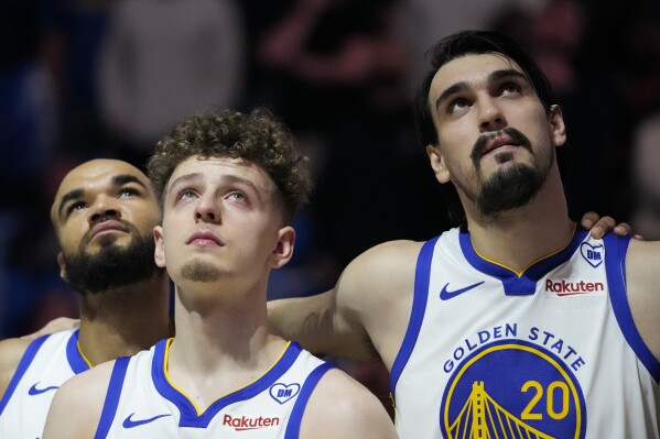 Golden State Warriors' Jerome Robinson, left to right, Brandin Podziemski and Dario Saric watch a video tribute for late assistant coach Dejan Milojevic, who died Jan. 17 after suffering a heart attack, before an NBA basketball game against the Atlanta Hawks, Wednesday, Jan. 24, 2024, in San Francisco. (AP Photo/Godofredo A. Vásquez)