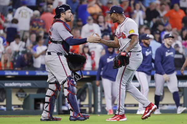 Atlanta Braves catcher Travis d'Arnaud, left, and closing pitcher Raisel Iglesias, right, celebrate after defeating the Houston Astros in a baseball game Wednesday, April 17, 2024, in Houston. The Braves won 5-4 in 10 innings. (AP Photo/Michael Wyke)