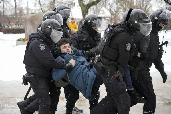 FILE - Police detain a man trying to lay flowers to honor Alexei Navalny at a monument in St. Petersburg, Russia, to victims of Soviet repression, on Saturday, Feb. 17, 2024. Over the last decade, Vladimir Putin's Russia evolved from a country that tolerates at least some dissent to one that ruthlessly suppresses it. Arrests, trials and long prison terms — once rare — are commonplace. (AP Photo, File)