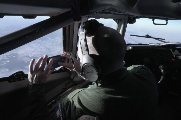 A crew member snaps a souvenir photo from the cockpit of a French military AWACS surveillance plane as it flies a 10-hour mission Tuesday, Jan. 9, 2024, to eastern Romania for the NATO military alliance. During the 2024 Olympics in July and August, France's AWACS will be used to provide an extra layer of radar surveillance over the Paris Games. (AP Photo/John Leicester)