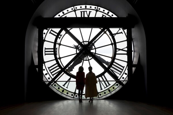 China's President Xi Jinping's wife Peng Liyuan, right, and French President Emmanuel Macron's wife Brigitte Macron pose in front of the clock as they visit the Orsay Museum, Monday, May 6, 2024 in Paris. (AP Photo/Aurelien Morissard, Pool)