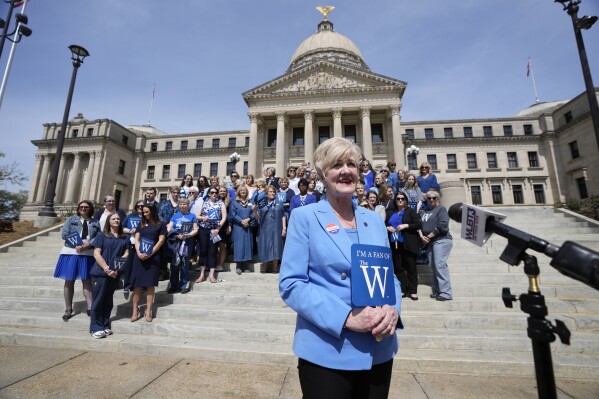 Mississippi University for Women President Nora Miller, center, stands with alumni on the steps of the Mississippi State Capitol, Tuesday, March 12, 2024, in Jackson, to address reporters. The group gathered at the statehouse in recognition of the Columbus, Miss., based school's 140th anniversary of the school's charter -- and to oppose a bill to merge the university with Mississippi State University. (AP Photo/Rogelio V. Solis)