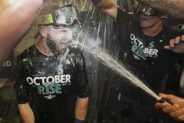 Seattle Mariners celebrate in the clubhouse after defeating the Toronto Blue Jays in Game 2 of a baseball AL wild-card playoff series Saturday, Oct. 8, 2022, in Toronto. (Nathan Denette/The Canadian Press via AP)