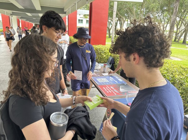 College students pass out Plan B to educate young voters at Florida Atlantic University on Thursday, April 11, 2024, in Boca Raton, Fla. Abortion and marijuana will be on Florida's November ballot, and these issues are critical issues for young voters. (AP Photo/Cody Jackson)
