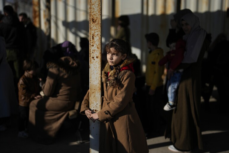 Syrians wait to cross into Syria from Turkey at the Oncupinar border gate, near the town of Kilis, southern Turkey, Monday, Dec. 9, 2024. (AP Photo/Khalil Hamra)