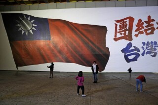 Children play in front of an image of a Taiwanese national flag as votes are counted in New Taipei City, Taiwan, Jan. 13, 2024. (AP Photo/Ng Han Guan)