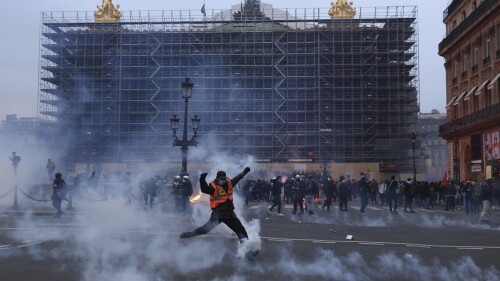 FILE - A protester kicks a tear gas canister in front of the Opera at the end of a rally against the pension reform in Paris, France, Thursday, March 23, 2023. French legislators are preparing to vote on a sweeping justice reform bill that would allow law enforcement agents to remotely tap into the camera, microphone, and location details from a suspect's phone and other connected devices. (AP Photo/Aurelien Morissard, File)