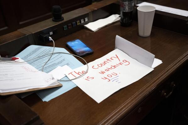 A sign rests on the desk of Rep. Gloria Johnson, D-Knoxville, in the House chamber as proceedings were brought to expel her from the legislature Thursday, April 6, 2023, in Nashville, Tenn. In an extraordinary act of political retaliation, Tennessee Republicans on Thursday expelled Rep. Justin Jones, a Democratic lawmaker from the state Legislature for his role in a protest that called for more gun control in the aftermath of a deadly school shooting in Nashville. Rep. Gloria Johnson narrowly avoided being removed. (AP Photo/George Walker IV)