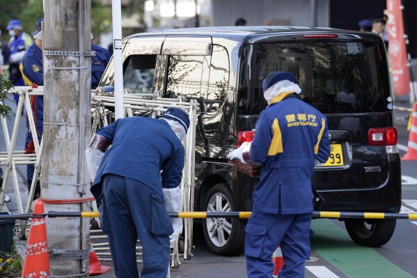 Police officers exam a car, rear, which crashed into a temporary barricade near the Israeli Embassy in Tokyo Thursday, Nov. 16, 2023. Police arrested the driver, according to reports. (AP Photo/Eugene Hoshiko)