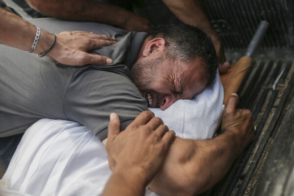 Palestinians mourn over the bodies of relatives killed in an Israeli airstrike, at a morgue in Al-Aqsa Martyrs Hospital in Deir al Balah, the Gaza Strip, Monday, June 10, 2024. (AP Photo/Jehad Alshrafi)