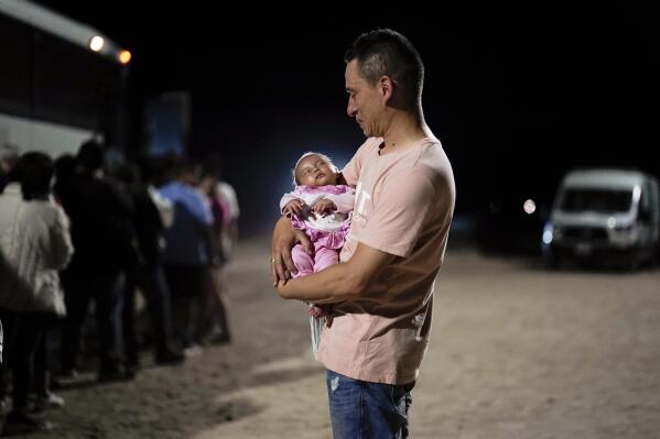 A migrant man from Colombia holds his baby daughter after crossing into the United States near the end of a border wall Tuesday, Aug. 23, 2022, near Yuma, Ariz. A border wall with Mexico isn't the issue it was during Donald Trump's presidency but plans for more barriers in Yuma, Ariz., is a reminder of obstacles that the federal government always faces: difficulty working on tribal lands and private property. (AP Photo/Gregory Bull)