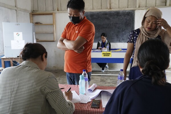 Presiding officer Neichutuonuo Yhome, 27, background, oversees a polling station as voters arrive to cast their votes in Chedema village, in the northeastern Indian state of Nagaland, Friday, April 19, 2024. (AP Photo/Yirmiyan Arthur)