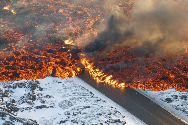 Lava crosses the main road to Grindavík and flows on the road leading to the Blue Lagoon, in Grindavík, Iceland, Thursday, Feb. 8, 2024. A volcano in southwestern Iceland has erupted for the third time since December and sent jets of lava into the sky. The eruption on Thursday morning triggered the evacuation the Blue Lagoon spa which is one of the island nation’s biggest tourist attractions. (AP Photo /Marco Di Marco)