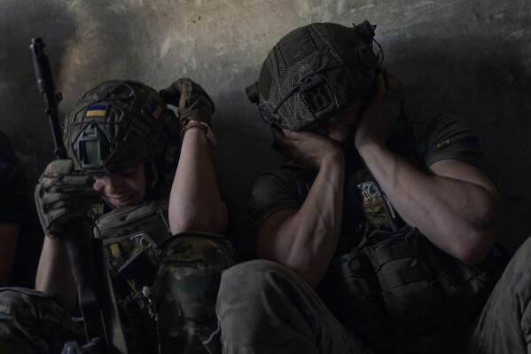 Ukrainian soldiers cover their ears to protect from the Russian tank shelling in a shelter on the frontline in the Zaporizhzhia region, Ukraine, Sunday, July 2, 2023. (AP Photo/Libkos)