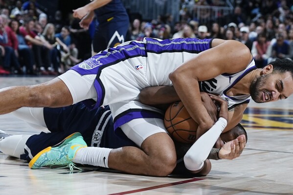 Sacramento Kings forward Trey Lyles, top, fights for control of a loose ball with Denver Nuggets forward Peyton Watson in the second half of an NBA basketball game Wednesday, Feb. 14, 2024, in Denver. (APPhoto/David Zalubowski)