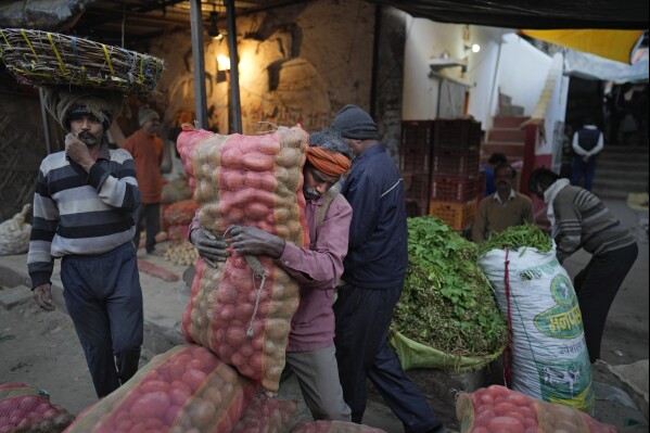 A laborer carries a sack of vegetables in Lucknow, capital of northern Indian state of Uttar Pradesh, Thursday, Feb. 29 2024. (AP Photo/Rajesh Kumar Singh)