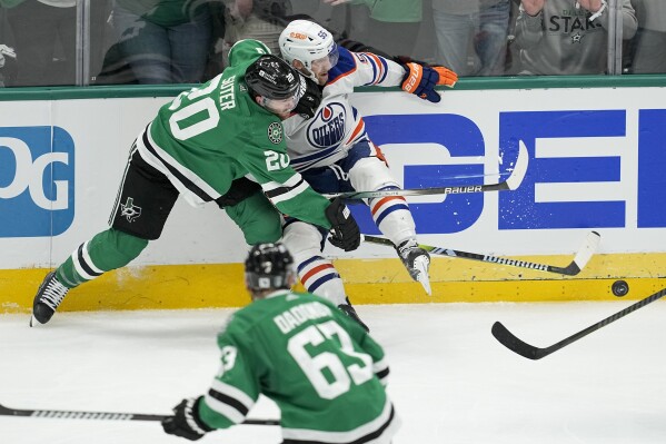 Dallas Stars defenseman Ryan Suter (20) collides with Edmonton Oilers left wing Dylan Holloway (55) as Stars' right wing Evgenii Dadonov (63) looks on during overtime in Game 1 of the NHL hockey Western Conference Stanley Cup playoff finals, Thursday, May 23, 2024, in Dallas. (AP Photo/Tony Gutierrez)