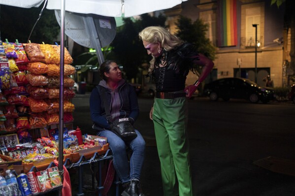 News anchor Guillermo Barraza, dressed as his drag character Amanda, stops to chat with candy vendor Mariela Soto, before entering the Rico nightclub to attend a drag queen performance, in Mexico City, Wednesday, Oct. 11, 2023. Barraza has sought to push the boundaries of society in a place where both LGBTQ+ people and journalists are violently targeted. (AP Photo/ Aurea Del Rosario)