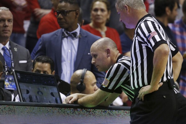 In this March 12, 2015, photo, officials review a play during an NCAA college basketball game between California and Arizona in the quarterfinals of the Pac-12 conference tournament in Las Vegas. (AP Photo/John Locher, File)