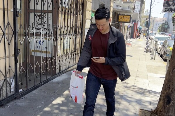 Andy Fang, DoorDash’s co-founder and chief technology officer, picks up and delivers food orders to customers in downtown San Francisco on Saturday, June 15, 2023. Fang is one of a growing number of executives who work shifts on the front lines of the companies they run. All DoorDash salaried employees are required to make deliveries or work directly with customers or merchants several times a year. (AP Photo/Terry Chea)