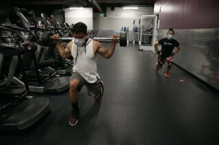 FILE - In this Friday, June 26, 2020 file photo, people wear masks while exercising at a gym in Los Angeles. On Thursday, July 9, 2020, the World Health Organization is acknowledging the possibility that COVID-19 might be spread in the air under certain conditions — after more than 200 scientists urged the agency to do so. (AP Photo/Jae C. Hong)