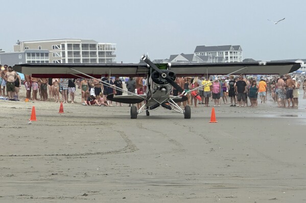 In this photo provided by Tammy Nowlan, a small plane sits on the beach after crashing, Saturday, July 29, 2023, in Hampton Beach, N.H. (Tammy Nowlan via AP)