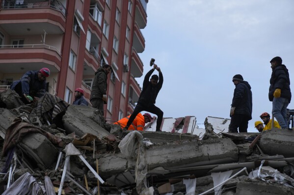 FILE - People and emergency teams search for victims under the rubble of a destroyed building in Adana, Turkey, Feb. 6, 2023. A year after the devastating 7.8 magnitude earthquake struck southern Turkey and northwestern Syria, a massive rebuilding effort is still trudging along. The quake caused widespread destruction and the loss of over 59,000 lives. (AP Photo/Khalil Hamra, File)