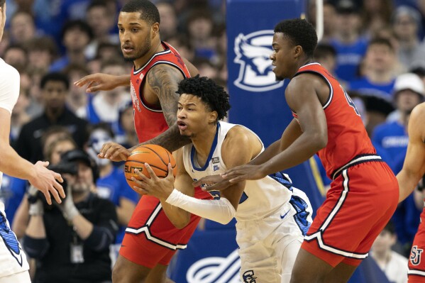 Creighton's Trey Alexander, center, passes the ball from between St. John's Joel Soriano, left, and Nahiem Alleyne during the first half of an NCAA college basketball game Saturday, Jan. 13, 2024, in Omaha, Neb. (AP Photo/Rebecca S. Gratz)