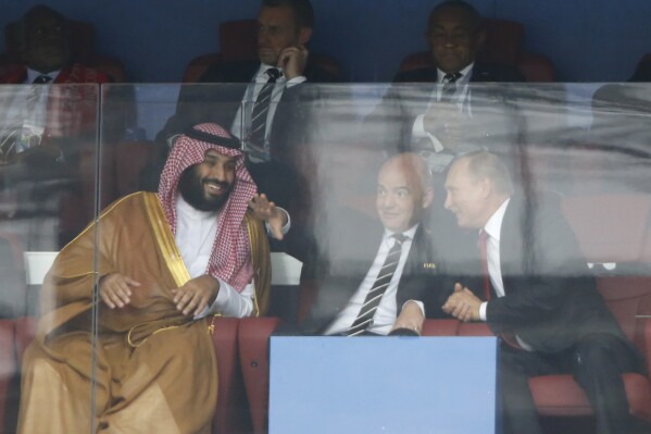 FILE - Saudi Arabia Crown Prince Mohammed bin Salman, left, FIFA President Gianni Infantino, center, and Russian President Vladimir Putin watch the match between Russia and Saudi Arabia which opens the 2018 soccer World Cup at the Luzhniki stadium in Moscow, Russia, on June 14, 2018. The near certainty that Saudi Arabia will host the 2034 men's World Cup unites two of the most influential men in world sports: the leader of soccer's governing body and the kingdom's crown prince. (AP Photo/Hassan Ammar, File)