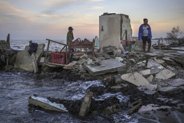 Yahir Mayoral and Emily Camacho walk amid the rubble of their grandmother's home, destroyed by flooding driven by a sea-level rise in their coastal community of El Bosque, in the state of Tabasco, Mexico, Thursday, Nov. 30, 2023. (AP Photo/Felix Marquez)