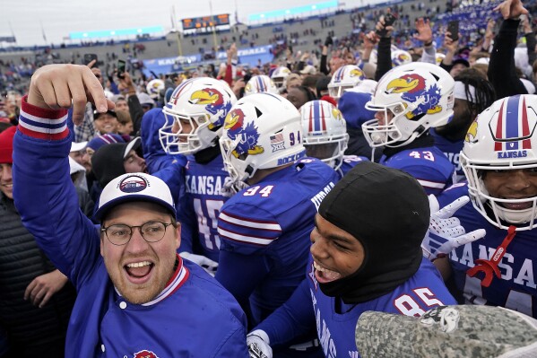 Kansas players celebrate with fans on the field after their NCAA college football game against Oklahoma Saturday, Oct. 28, 2023, in Lawrence, Kan. Kansas won 38-33. (AP Photo/Charlie Riedel)