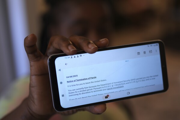 Haitian immigrant Nicole, who works for a meat processing plant, shows an email terminating her parole, Sunday, April 13, 2025, in Dumas, Texas. (AP Photo/Eric Gay)