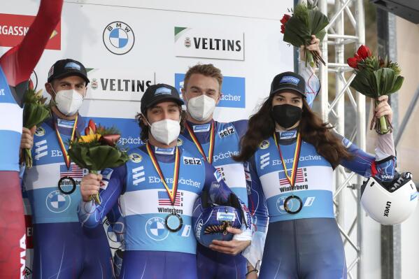 The third placed team from the USA (Summer Britcher, Tucker West, Christopher Mazdzer, Jayson Terdiman) stand on the podium during the award ceremony after the mixed relay competition of the Luge World Cup in Winterberg, Germany, Sunday, Jan. 2, 2022. (Friso Gentsch/dpa via AP)