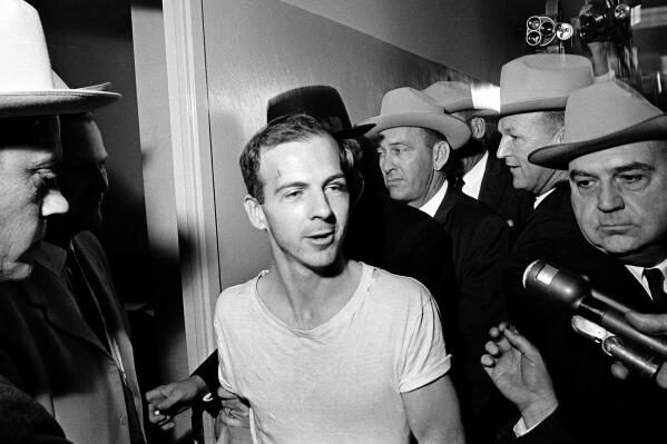 FILE — Surrounded by detectives, Lee Harvey Oswald talks to the media as he is led down a corridor of the Dallas police station, Nov. 23, 1963, for another round of questioning in connection with the assassination of U.S. President John F. Kennedy. The life insurance policy on the man who assassinated Kennedy paid out less than $900 to his mother, but the death claim she filed to get that sum has sold at auction for almost $80,000. The original Notice of Insurance Claim for Lee Harvey Oswald sold for $79,436 on Wednesday, April 13, 2022, Boston-based RR Auction said in a statement. (AP Photo/File)