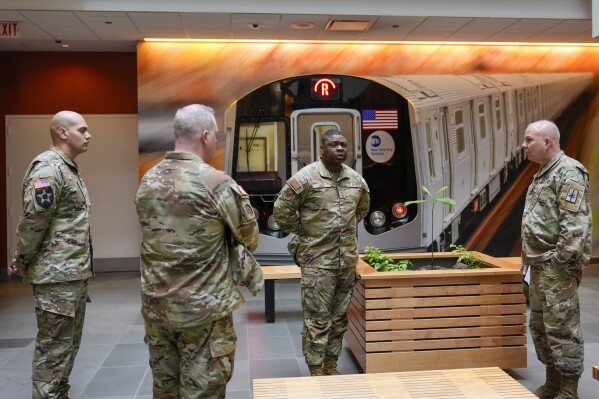 Members of the Armed Forces including the National Guard wait in the lobby of the New York City Mass Transit Authority Rail Control Center before the start of a news conference with Gov. Hochul, Wednesday, March 6, 2024, in New York. Hochul is deploying the National Guard to the New York City subway system to help police search passengers' bags for weapons, following a series of high profile crimes on city trains. (AP Photo/Mary Altaffer)