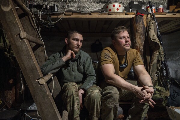 Ukrainian servicemen from the Azov brigade known by call sign Ray, left, and Kiss, right, rest in the trenches on the frontline in Kreminna direction, Donetsk region, Ukraine, Thursday, April 11, 2024. (AP Photo/Alex Babenko)