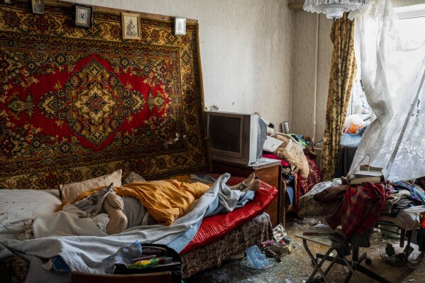 The body of a woman that died after a Russian attack at a residential area lies on a bed surrounded by debris in Uman, central Ukraine, Friday, April 28, 2023. (AP Photo/Bernat Armangue)
