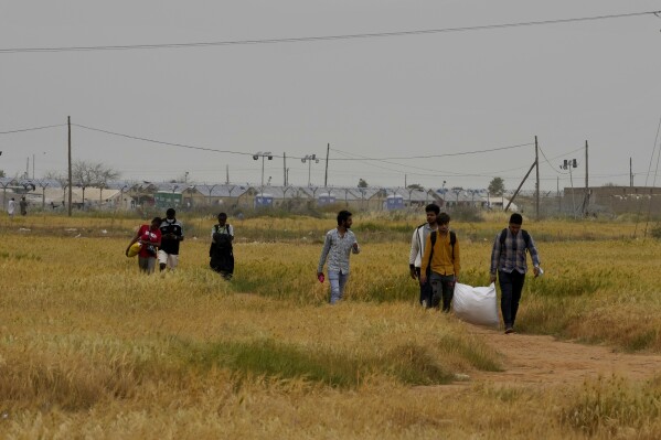 FILE - Migrants walk near the Pournara Emergency Reception center, in Kokkinotrimithia, on the outskirts of the capital Nicosia, Cyprus, April 18, 2022. The United Nations refugee agency said Friday, Aug. 11, 2023, it was “extremely concerned” over the return of more than 100 Syrian nationals from Cyprus to Lebanon without being screened to determine whether they need legal protection and who may be deported back to their war-wracked homeland. (AP Photo/Petros Karadjias, File)