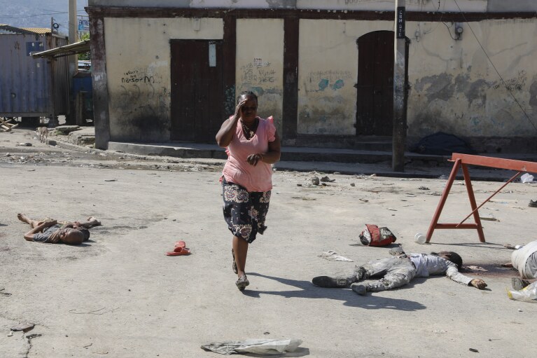 A woman walks past bodies of inmates outside the National Penitentiary in Port-au-Prince, Haiti, Sunday, March 3, 2024. (AP Photo/Odelyn Joseph)